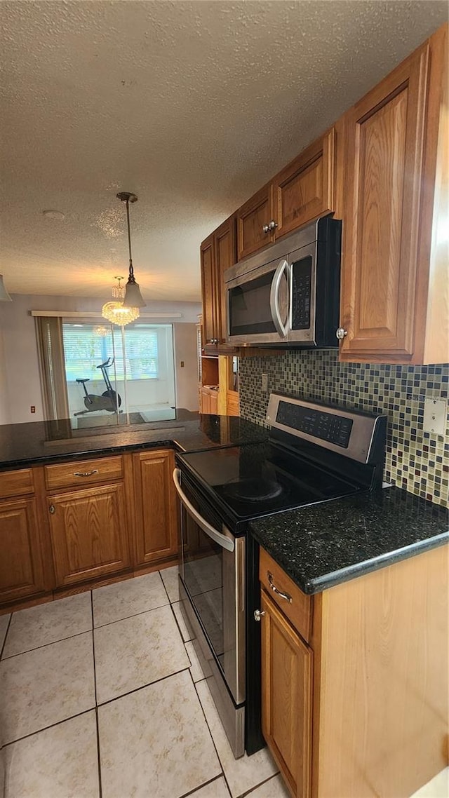 3123 29th Ave N Unit 105, Saint Petersburg, FL 33713 - kitchen featuring appliances with stainless steel finishes, brown cabinetry, decorative backsplash, and a textured ceiling