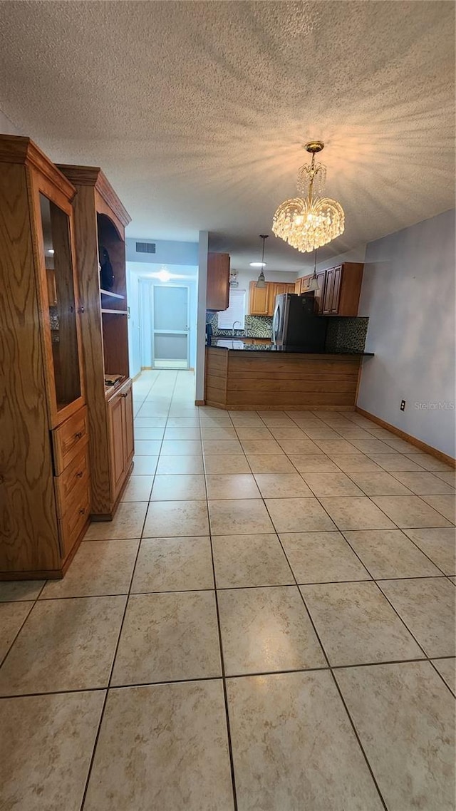 3123 29th Ave N Unit 105, Saint Petersburg, FL 33713 - kitchen featuring freestanding refrigerator, a chandelier, brown cabinetry, a textured ceiling, and dark countertops