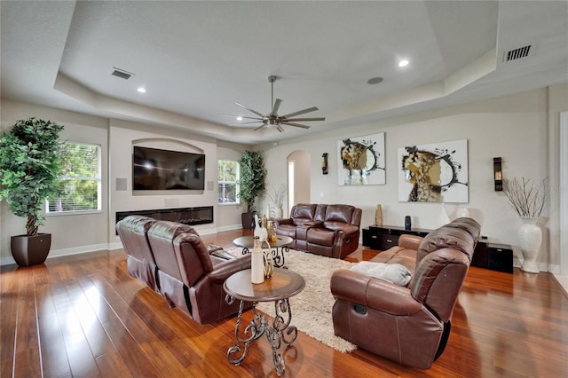 13102 Done Groven Dr, Dover, FL 33527 - living room featuring a tray ceiling, wood finished floors, arched walkways, healthy amount of natural light, and recessed lighting