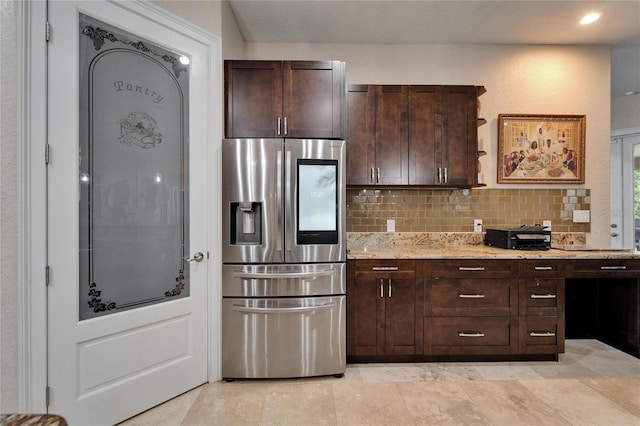 13102 Done Groven Dr, Dover, FL 33527 - kitchen with stainless steel refrigerator with ice dispenser, backsplash, dark brown cabinets, and light stone countertops
