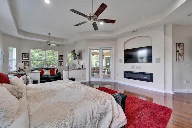 13102 Done Groven Dr, Dover, FL 33527 - bedroom featuring a tray ceiling, wood finished floors, recessed lighting, a glass covered fireplace, and a ceiling fan