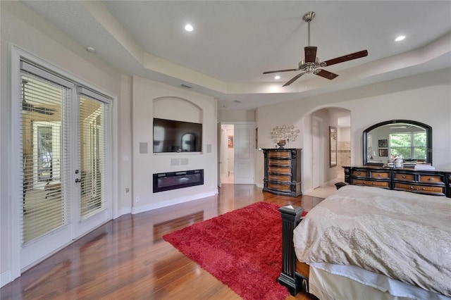 13102 Done Groven Dr, Dover, FL 33527 - bedroom featuring access to exterior, a tray ceiling, arched walkways, wood finished floors, and recessed lighting