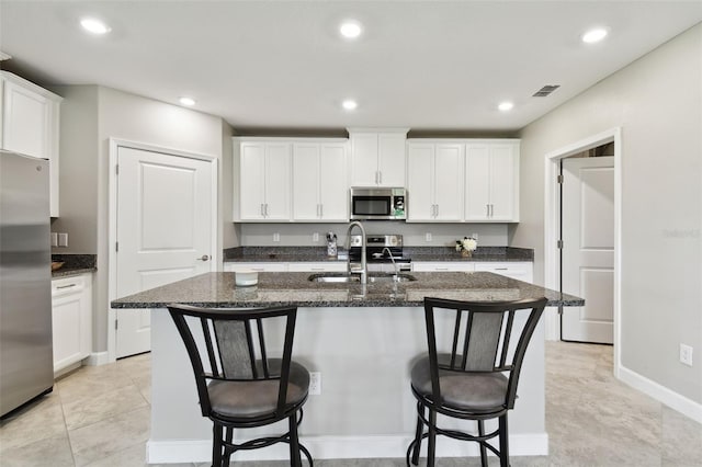 10282 Echo Dock Loop, San Antonio, FL 33576 - kitchen with appliances with stainless steel finishes, a kitchen island with sink, a kitchen bar, white cabinets, and recessed lighting