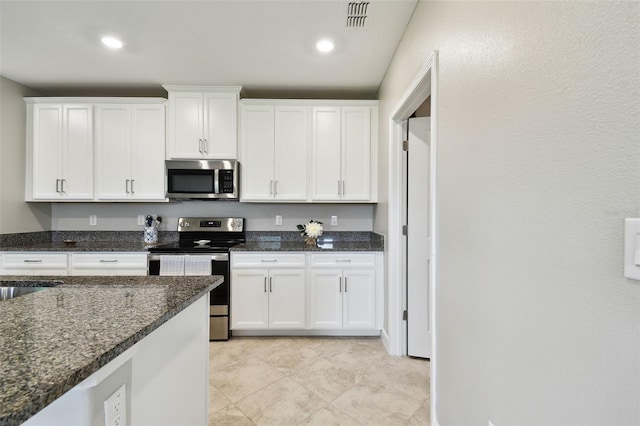 10282 Echo Dock Loop, San Antonio, FL 33576 - kitchen with stainless steel appliances, white cabinets, dark stone counters, and recessed lighting