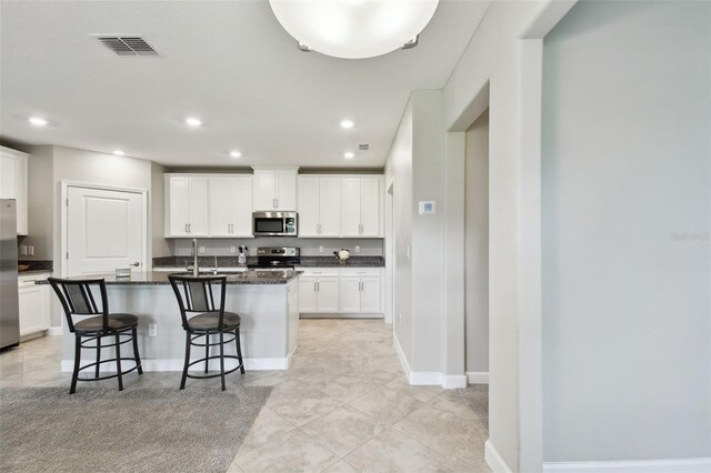 10282 Echo Dock Loop, San Antonio, FL 33576 - kitchen with stainless steel appliances, white cabinetry, a kitchen breakfast bar, a center island with sink, and recessed lighting