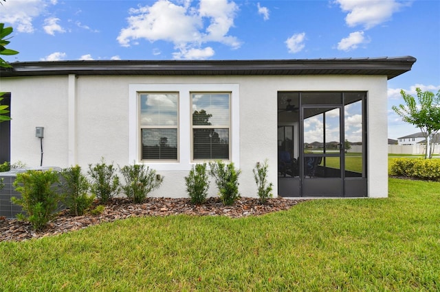 10282 Echo Dock Loop, San Antonio, FL 33576 - view of home's exterior featuring stucco siding, a lawn, and a sunroom