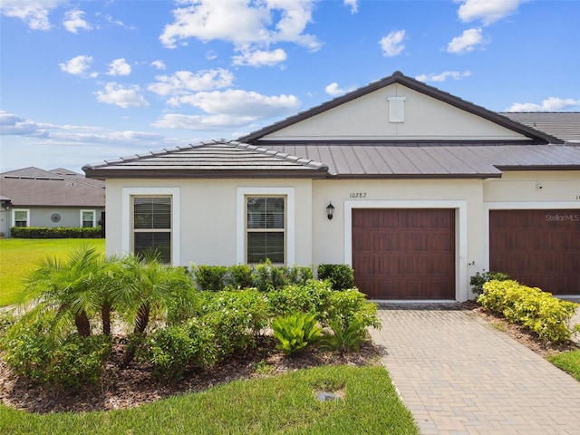 10282 Echo Dock Loop, San Antonio, FL 33576 - view of front of property featuring stucco siding, decorative driveway, an attached garage, and a metal roof