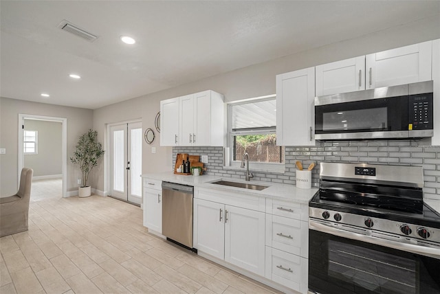 2905 Forest Cir, Seffner, FL 33584 - kitchen with stainless steel appliances, decorative backsplash, white cabinets, recessed lighting, and light wood-style floors