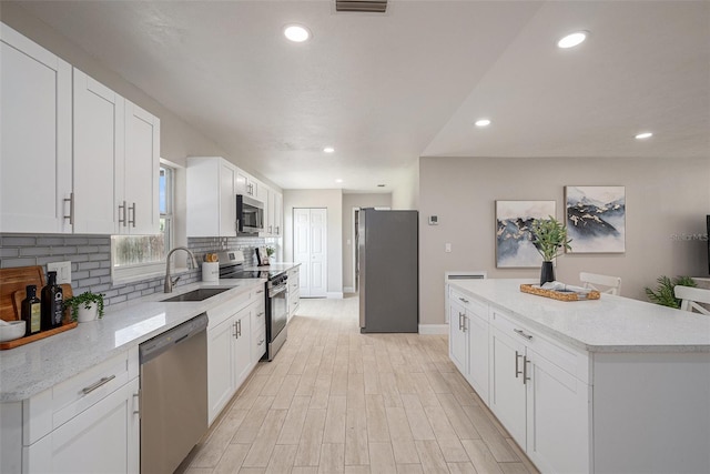 2905 Forest Cir, Seffner, FL 33584 - kitchen with appliances with stainless steel finishes, backsplash, white cabinets, recessed lighting, and light wood-type flooring