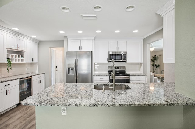 852 Crystal Dr, Palm Harbor, FL 34683 - kitchen with stainless steel appliances, beverage cooler, backsplash, white cabinets, and light wood-style floors