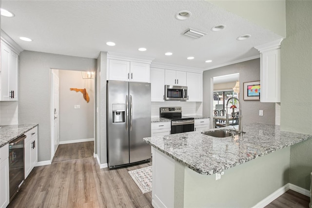 852 Crystal Dr, Palm Harbor, FL 34683 - kitchen featuring appliances with stainless steel finishes, a peninsula, light wood-style floors, white cabinets, and recessed lighting