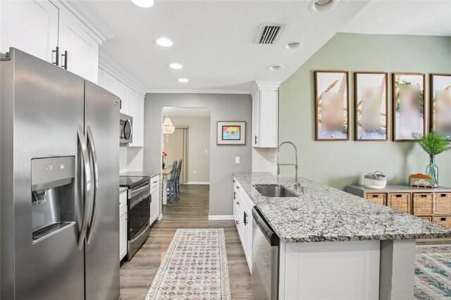 852 Crystal Dr, Palm Harbor, FL 34683 - kitchen with appliances with stainless steel finishes, a peninsula, white cabinets, light wood-style floors, and recessed lighting