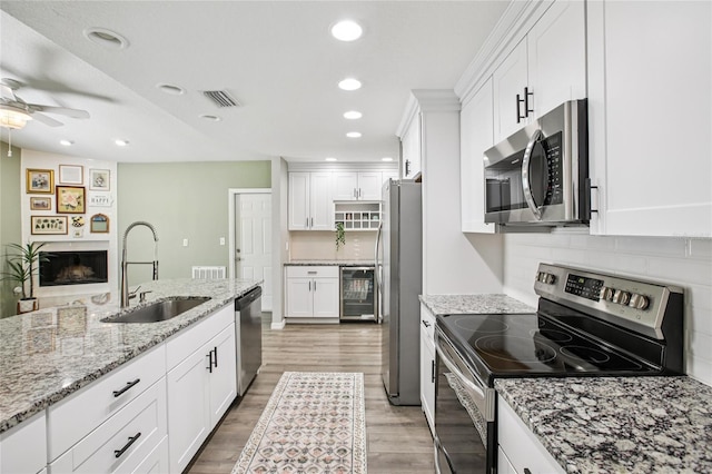 852 Crystal Dr, Palm Harbor, FL 34683 - kitchen with stainless steel appliances, ceiling fan, white cabinetry, light wood-type flooring, and wine cooler