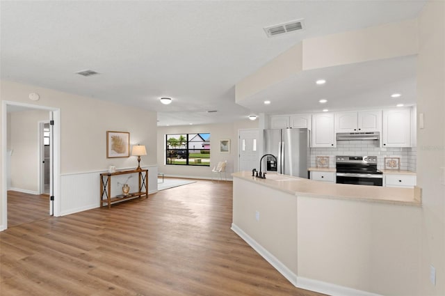4530 Zack Dr, New Port Richey, FL 34653 - kitchen featuring appliances with stainless steel finishes, under cabinet range hood, white cabinetry, light wood finished floors, and light countertops