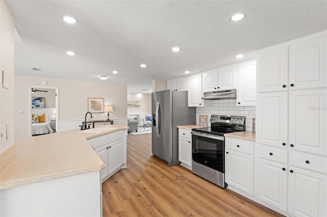 4530 Zack Dr, New Port Richey, FL 34653 - kitchen featuring appliances with stainless steel finishes, under cabinet range hood, a textured ceiling, light countertops, and light wood-style flooring