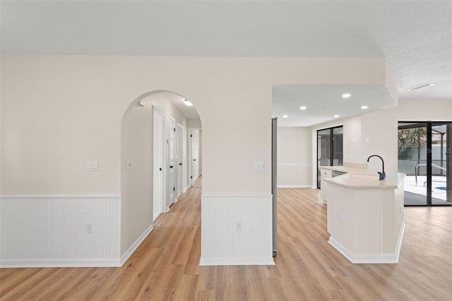 4530 Zack Dr, New Port Richey, FL 34653 - kitchen with light wood-style flooring, a wainscoted wall, light countertops, arched walkways, and recessed lighting