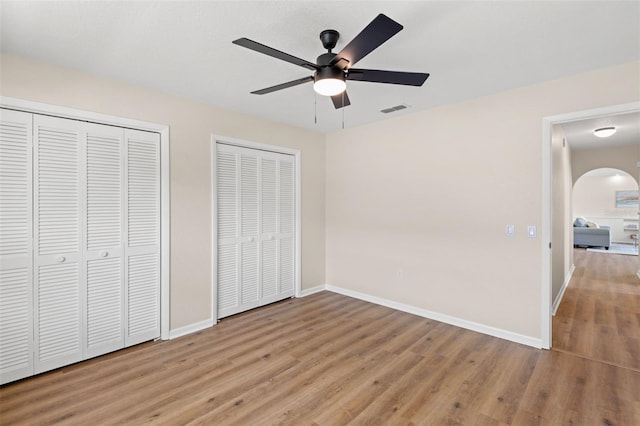 4530 Zack Dr, New Port Richey, FL 34653 - unfurnished bedroom featuring two closets, wood finished floors, arched walkways, and ceiling fan