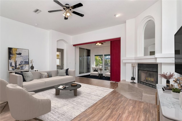 211 Arlington Ave E, Oldsmar, FL 34677 - living room featuring arched walkways, wood finished floors, ceiling fan, and a tiled fireplace