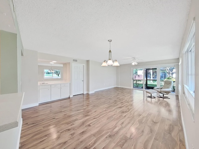 700 Starkey Rd Unit 311, Largo, FL 33771 - unfurnished living room featuring a textured ceiling, a chandelier, healthy amount of natural light, light wood finished floors, and ceiling fan