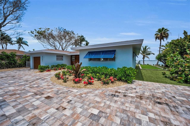 4381 Poinsettia Dr, St Pete Beach, FL 33706 - view of front of property featuring a garage, driveway, stucco siding, and a front lawn