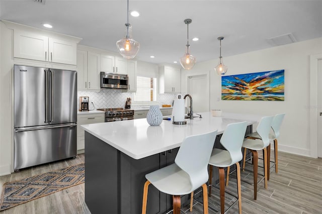 4381 Poinsettia Dr, St Pete Beach, FL 33706 - kitchen featuring high quality appliances, light wood finished floors, decorative backsplash, a breakfast bar area, and light countertops