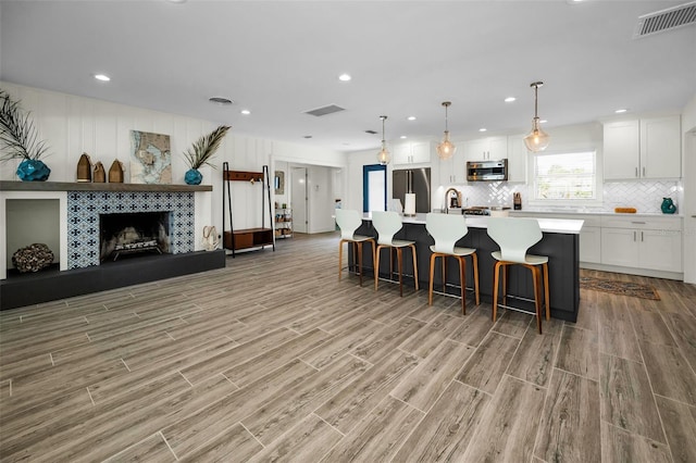 4381 Poinsettia Dr, St Pete Beach, FL 33706 - kitchen with appliances with stainless steel finishes, light wood finished floors, white cabinets, backsplash, and a breakfast bar