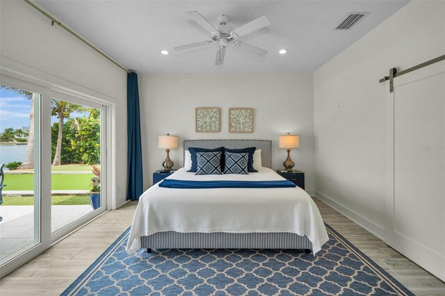 4381 Poinsettia Dr, St Pete Beach, FL 33706 - bedroom featuring a barn door, access to outside, light wood finished floors, recessed lighting, and ceiling fan