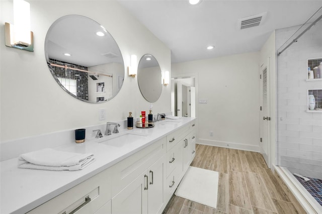 4381 Poinsettia Dr, St Pete Beach, FL 33706 - full bath with double vanity, wood finished floors, recessed lighting, and tiled shower