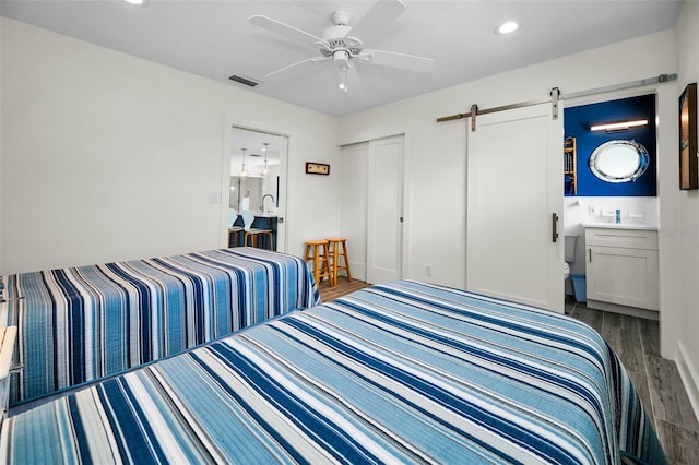 4381 Poinsettia Dr, St Pete Beach, FL 33706 - bedroom with a barn door, wood finished floors, recessed lighting, ceiling fan, and ensuite bathroom