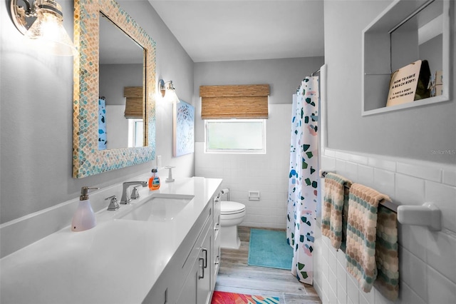4381 Poinsettia Dr, St Pete Beach, FL 33706 - full bath with tile walls, vanity, wood finished floors, a wainscoted wall, and curtained shower