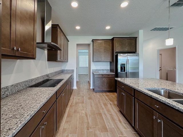38120 Shale Stone Ct, Zephyrhills, FL 33540 - kitchen with wall chimney range hood, stainless steel fridge, black electric stovetop, dark brown cabinets, and light wood finished floors