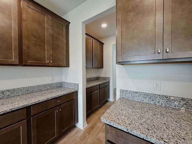 38120 Shale Stone Ct, Zephyrhills, FL 33540 - kitchen featuring light wood-type flooring, dark brown cabinets, light stone counters, and recessed lighting