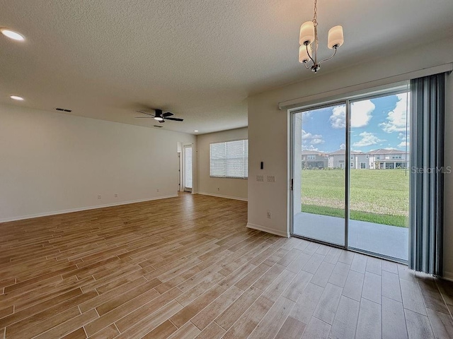 38120 Shale Stone Ct, Zephyrhills, FL 33540 - empty room with ceiling fan, light wood-style flooring, a textured ceiling, a chandelier, and recessed lighting