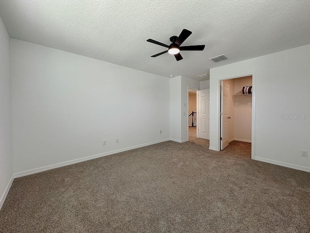 38120 Shale Stone Ct, Zephyrhills, FL 33540 - unfurnished bedroom with carpet floors, a spacious closet, a textured ceiling, a closet, and a ceiling fan