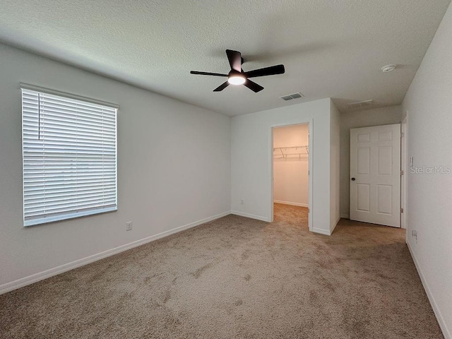 38120 Shale Stone Ct, Zephyrhills, FL 33540 - unfurnished bedroom with a walk in closet, carpet floors, a closet, a ceiling fan, and a textured ceiling