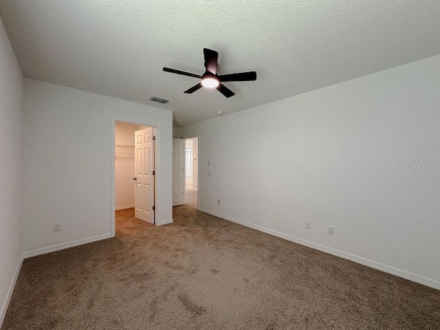 38120 Shale Stone Ct, Zephyrhills, FL 33540 - unfurnished bedroom with a walk in closet, carpet, a ceiling fan, a closet, and a textured ceiling