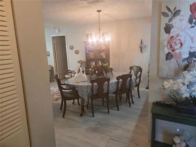 12133 Spartan Way Unit 203, Hudson, FL 34667 - dining space with a textured ceiling, a chandelier, and light wood-style floors
