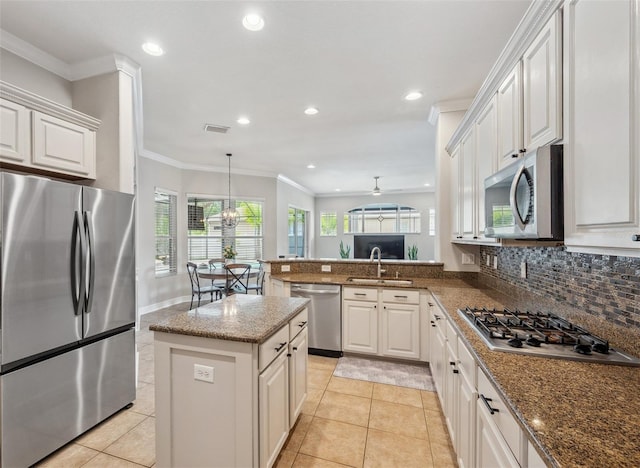 31646 Baymont Loop, Wesley Chapel, FL 33543 - kitchen featuring appliances with stainless steel finishes, a peninsula, crown molding, decorative backsplash, and dark stone countertops