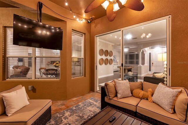 31646 Baymont Loop, Wesley Chapel, FL 33543 - living area featuring a textured wall, ceiling fan, stone tile flooring, and decorative columns