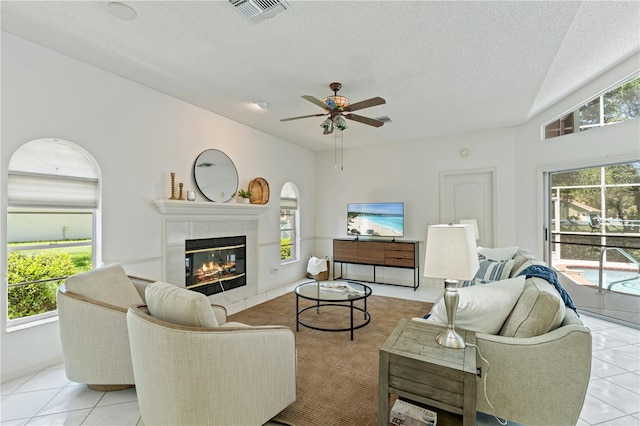 18561 Winding Oaks Blvd, Hudson, FL 34667 - living area with light tile patterned flooring, a ceiling fan, a tiled fireplace, and a textured ceiling