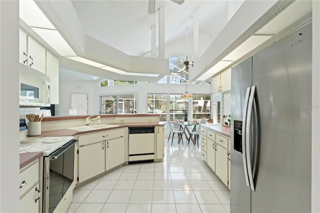 18561 Winding Oaks Blvd, Hudson, FL 34667 - kitchen featuring white appliances, light tile patterned floors, ceiling fan, a peninsula, and high vaulted ceiling