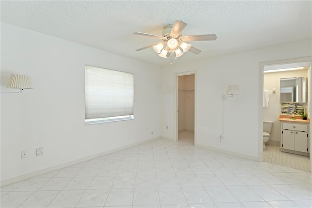 18561 Winding Oaks Blvd, Hudson, FL 34667 - unfurnished bedroom with a walk in closet, a closet, a ceiling fan, a textured ceiling, and ensuite bathroom