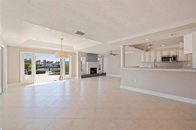 11225 4th St E, Treasure Island, FL 33706 - unfurnished living room with a raised ceiling, crown molding, light tile patterned flooring, a ceiling fan, and a fireplace with raised hearth