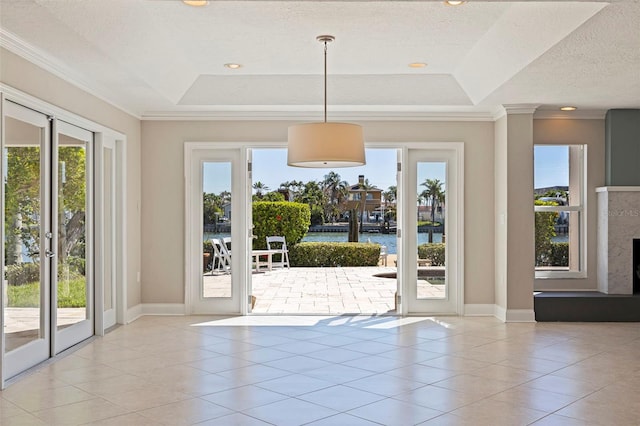 11225 4th St E, Treasure Island, FL 33706 - doorway with a raised ceiling, tile patterned floors, crown molding, a water view, and a fireplace with raised hearth