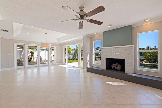 11225 4th St E, Treasure Island, FL 33706 - unfurnished living room featuring crown molding, a raised ceiling, ceiling fan, a high end fireplace, and light tile patterned floors
