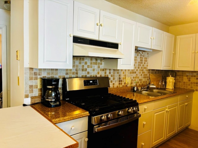 5623 80th St N Unit 406, Saint Petersburg, FL 33709 - kitchen with gas range, under cabinet range hood, white cabinets, tasteful backsplash, and a textured ceiling