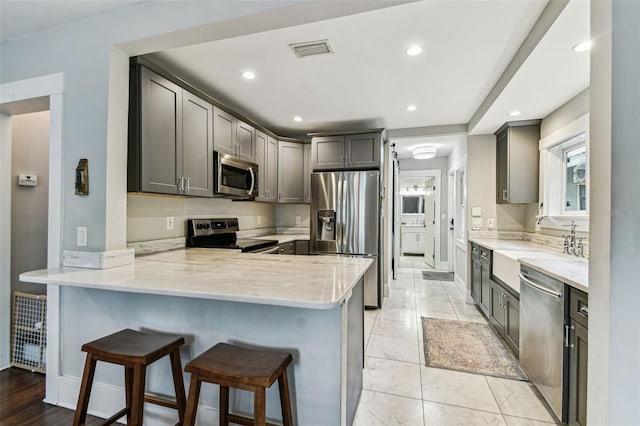 711 S Bungalow Ter, Tampa, FL 33606 - kitchen with appliances with stainless steel finishes, a peninsula, a breakfast bar area, recessed lighting, and light stone counters