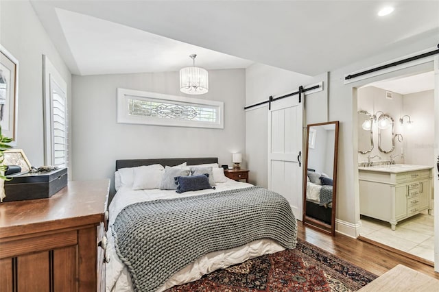711 S Bungalow Ter, Tampa, FL 33606 - bedroom featuring a barn door, light wood-style floors, connected bathroom, vaulted ceiling, and a chandelier