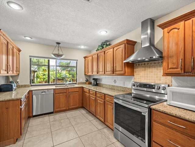4209 Winding Willow Dr, Tampa, FL 33618 - kitchen with stainless steel appliances, wall chimney exhaust hood, brown cabinetry, decorative backsplash, and recessed lighting
