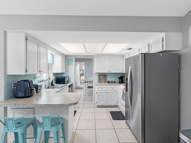 9109 134th Way, Seminole, FL 33776 - kitchen with stainless steel appliances, a peninsula, tasteful backsplash, light countertops, and light tile patterned flooring